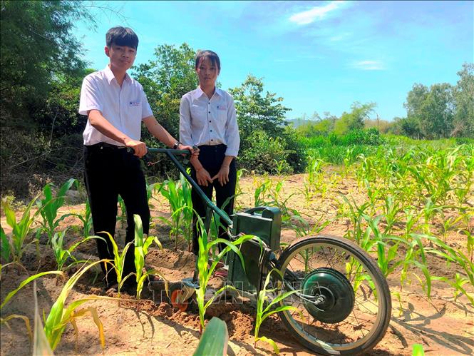 Em Phạm Thị Hoài Phương và Lê Tuấn Kiệt với máy cày điện để làm cỏ, bón phân.